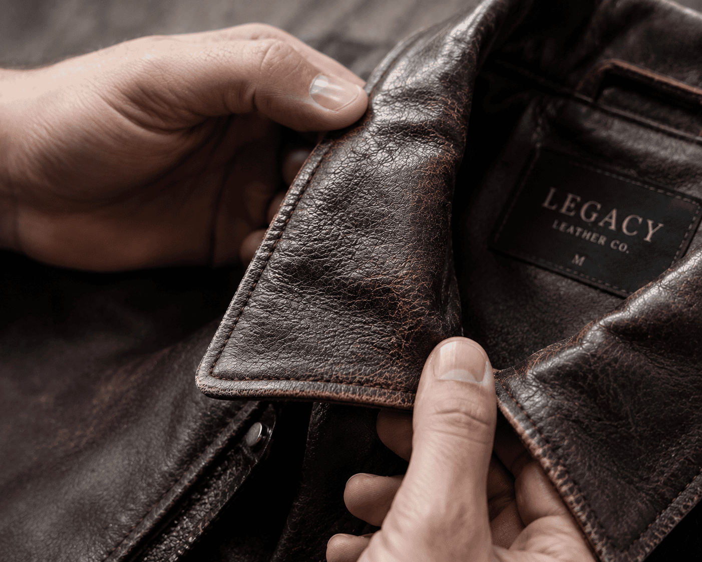Close-up examination of leather jacket showing grain texture versus synthetic material differences